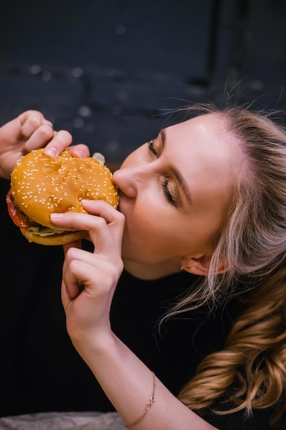 A young girl holds a burger with a meat patty in her handsDelicious and hearty lunch Fast food and snacks