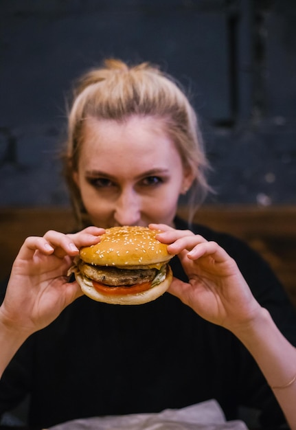 A young girl holds a burger with a meat patty in her handsDelicious and hearty lunch