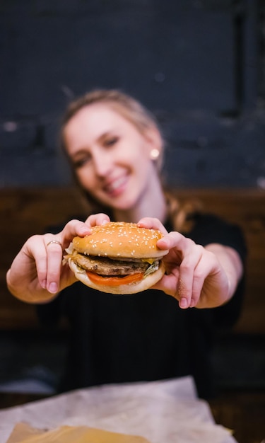 A young girl holds a burger with a meat patty in her handsDelicious and hearty lunch