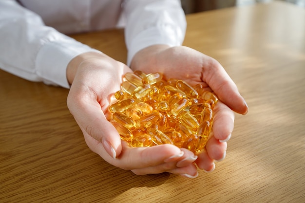 A young girl holds in her palms a lot of fish oil capsules.