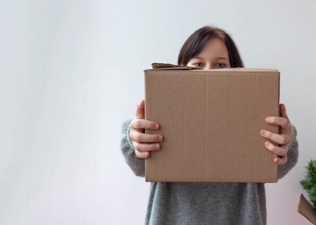 A young girl holds out a cardboard box delivery concept