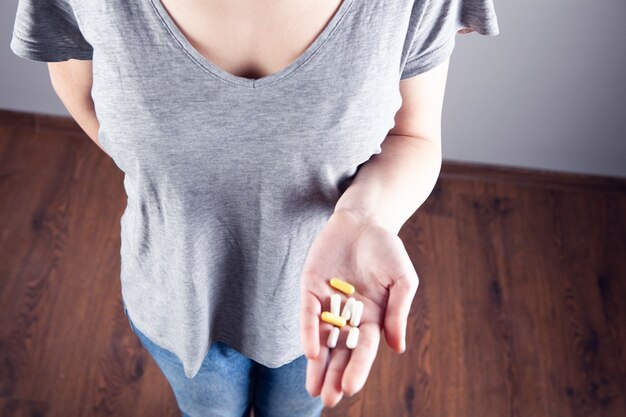 Young girl holds pills in her hand. view from above