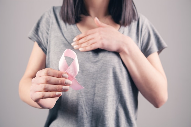 Young girl holds a pink ribbon on a gray