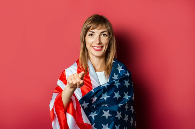 Young girl holds the US flag on a pink background. 