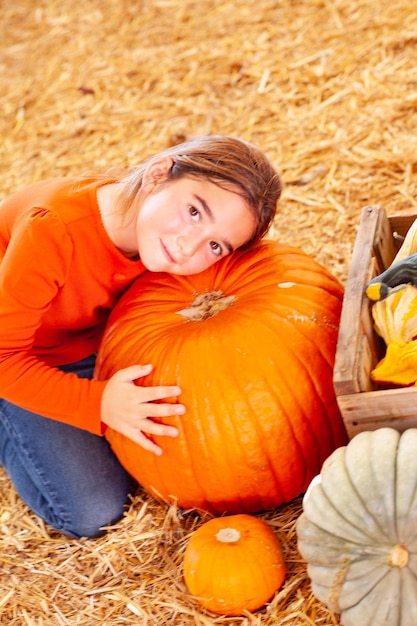 Young Girl Hugging a Big Pumpkin at the Pumpkin Patch