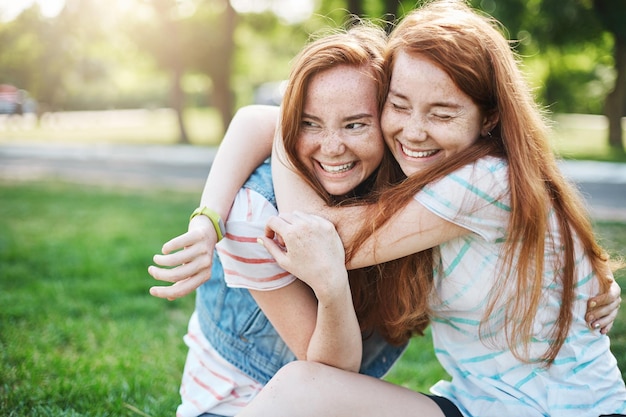 Young girl hugging her older sister smiling Two red haired ladies having the best time of their lives