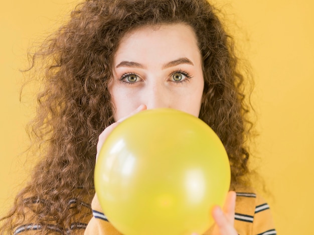 Young girl inflates a yellow balloon