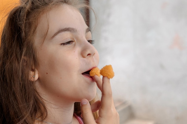 Young girl is holding yellow raspberries on her fingers and tasting