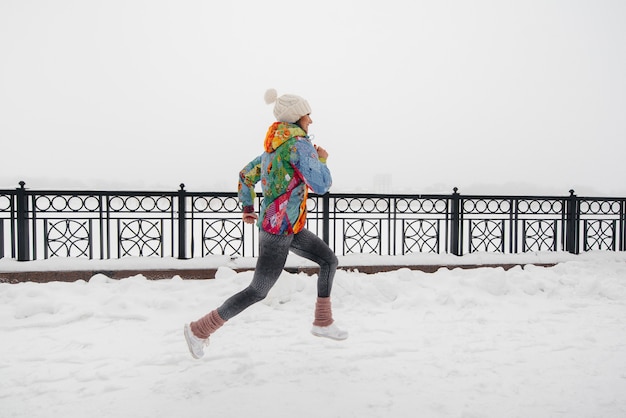 A young girl is Jogging on frosty and snowy day. Sports, healthy lifestyle. 