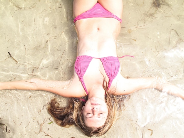 A young girl is laying on the beach