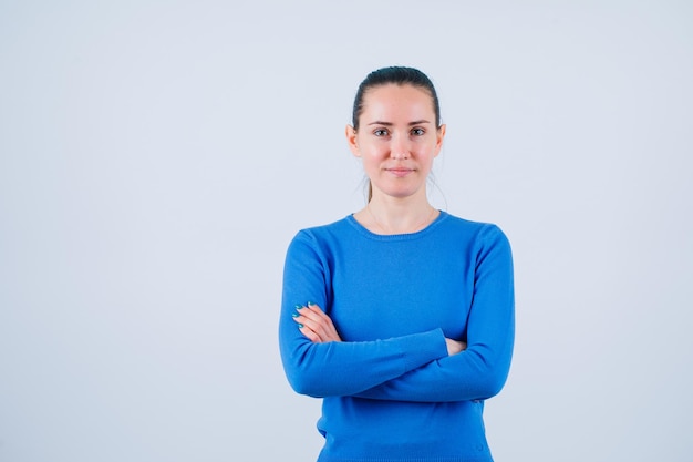 Young girl is looking at camera by crossing arms on white background