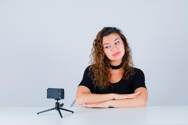 Young girl is looking at her mini camera on white background