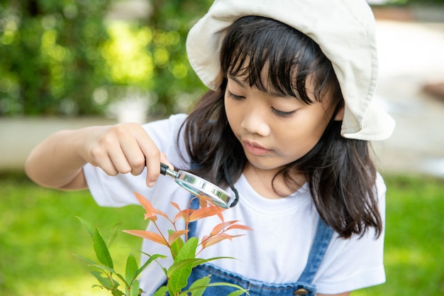 若い女の子は拡大鏡、屋外撮影を通して木の葉を見ています