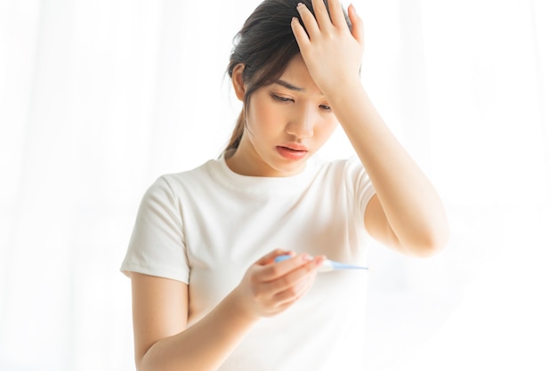 Young girl is measuring herself temperature