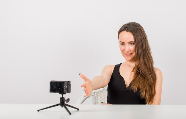 Young girl is posing at camera by extending hand to camera on white background