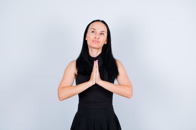 Young girl is praying by looking up and holding hands together on chest on white background