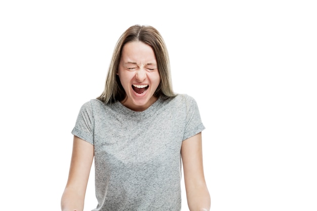 The young girl is screaming emotionally. Isolated on a white wall. Anger and resentment.