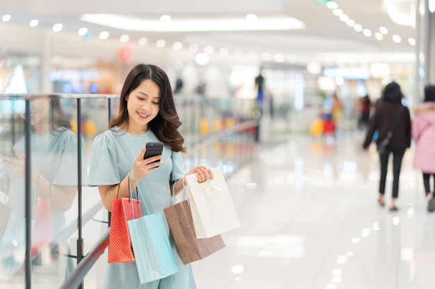 Young girl is shopping and using the phone at the mall