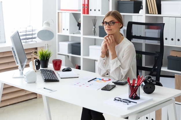 A young girl is sitting at the computer desk in the office