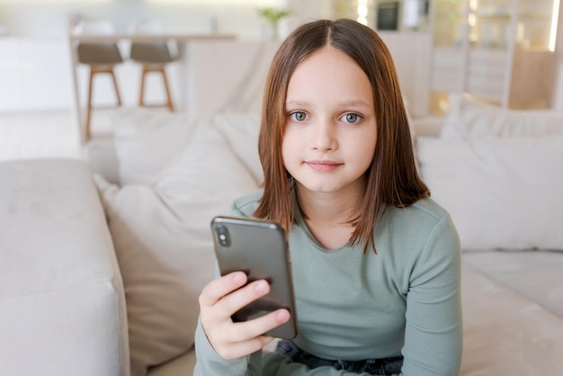 若い女の子がソファに座って携帯電話を持っています
