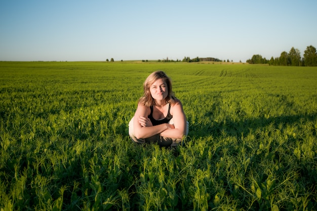 Photo a young girl is sitting in a green field on a summer morning