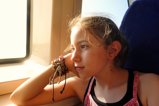 Young Girl is Sitting near the Ferry Window and Soft Sunlight Comes to her face