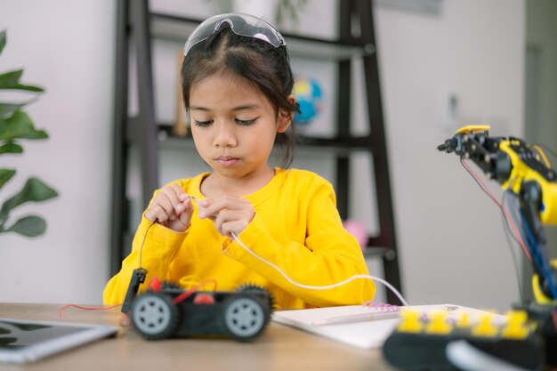 若い女の子が黄色いシャツを着てロボットに取り組んでいる