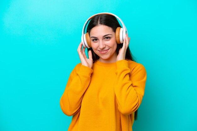 Young girl isolated on blue background listening music