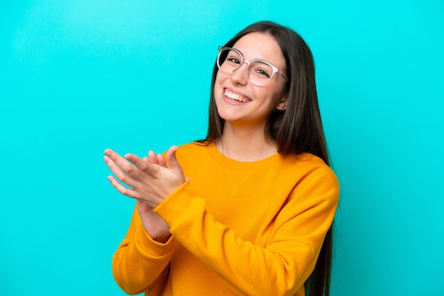 メガネと拍手で青の背景に分離された若い女の子