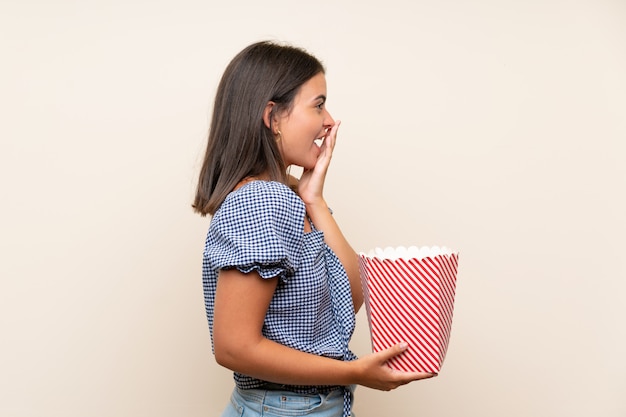 Молодая девушка за изолированной стеной держит миску попкорна