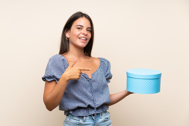 Young girl over isolated wall holding gift box