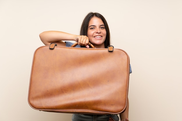 Young girl over isolated wall holding a vintage briefcase