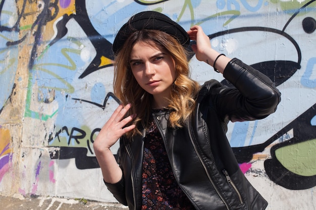 Young girl in a jacket with the graffiti on the background