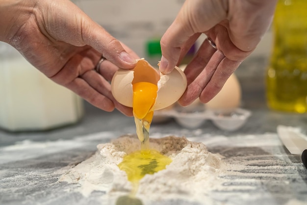 Young girl in the kitchen breaks eggs and sprinkles flour to bake a cool birthday cake The concept of cooking in the kitchen