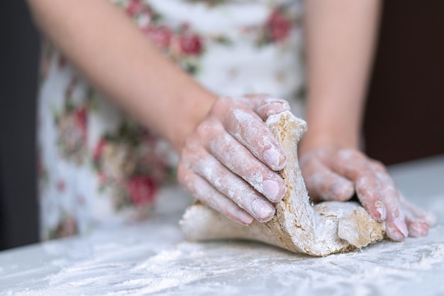 A young girl kneads dough with her hands