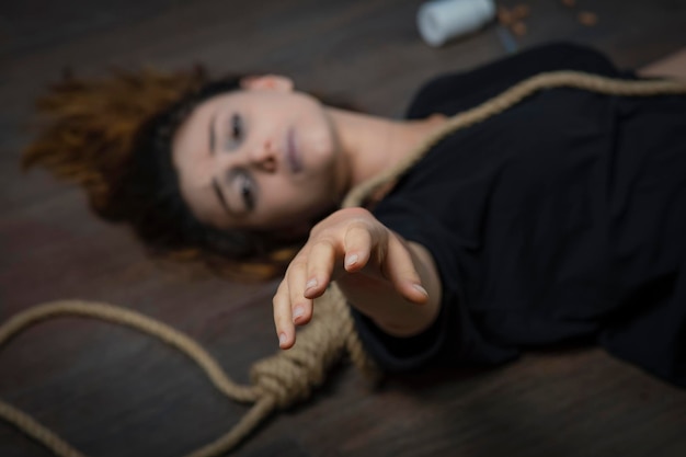 Photo young girl laying on the ground with hangman's knot and ask him for help. high quality photo