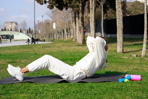 Young girl laying on mat and doing situps at the park High quality photo