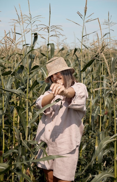 Photo young girl in a linen suit and a hat on a summer sunny day stands in a corn field love of travel and