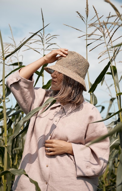 Young girl in a linen suit and a hat on a summer sunny day stands in a corn field love of travel and