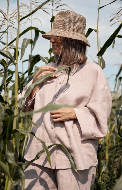 Young girl in a linen suit and a hat on a summer sunny day stands in a corn field love of travel and