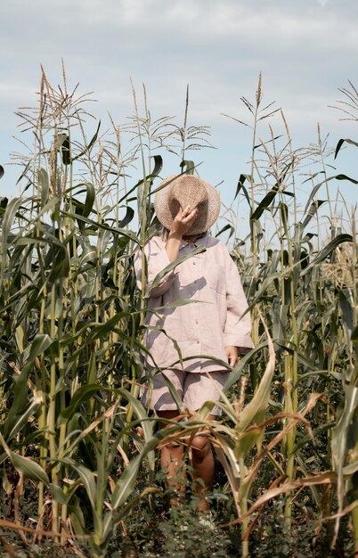 Young girl in a linen suit and a hat on a summer sunny day stands in a corn field love of travel and