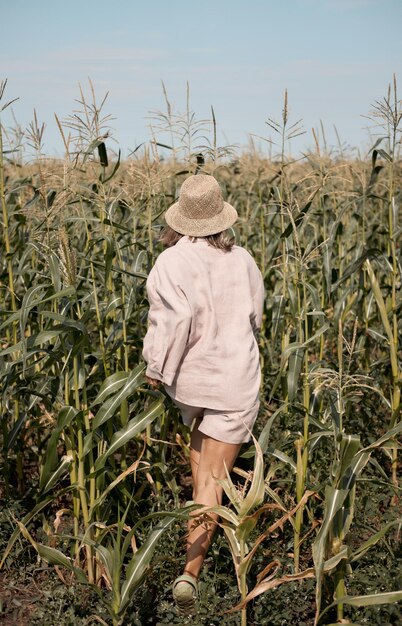 Young girl in a linen suit and a hat on a summer sunny day stands in a corn field love of travel and