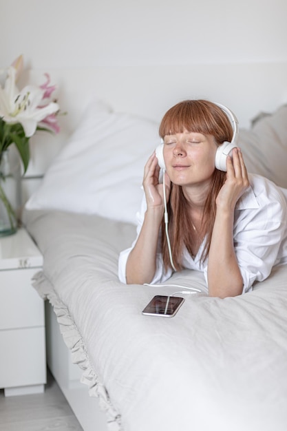 Photo young girl listening to music in bed flower lily indoor