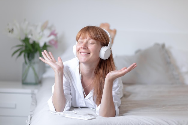 Фото Молодая девушка слушает музыку в постели цветочная лилия в помещении