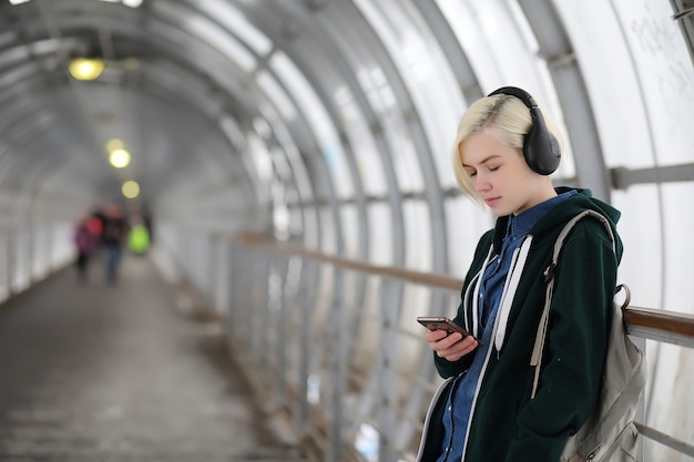 La ragazza ascolta musica in grandi cuffie nel tunnel della metropolitana