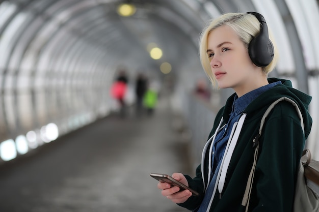 Foto la ragazza ascolta musica in grandi cuffie nel tunnel della metropolitana