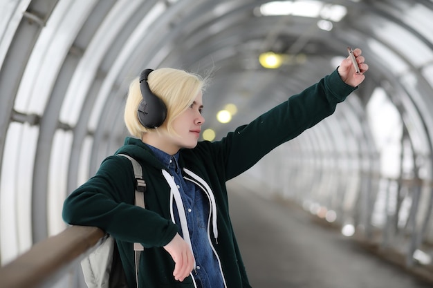 Young girl listens to music in big headphones in the subway