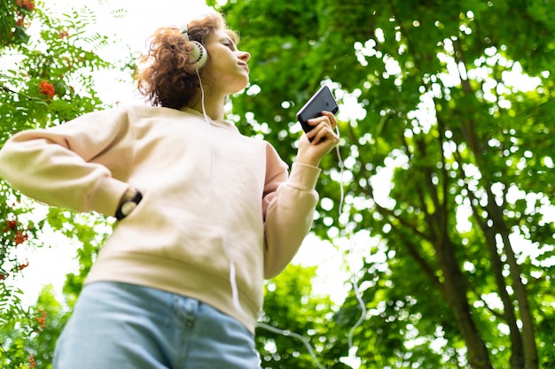 La ragazza ascolta musica con grandi auricolari e balli