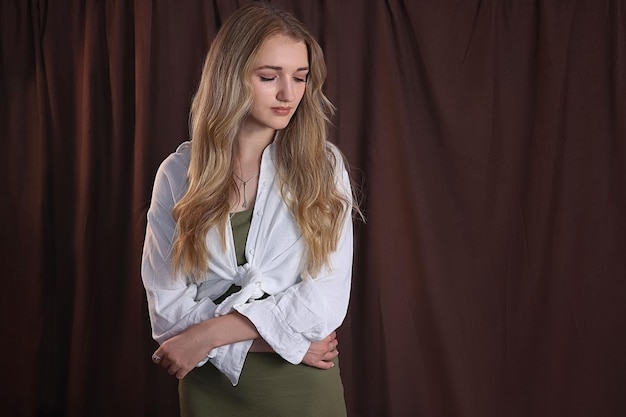 The young girl looked down. Standing on a brown background