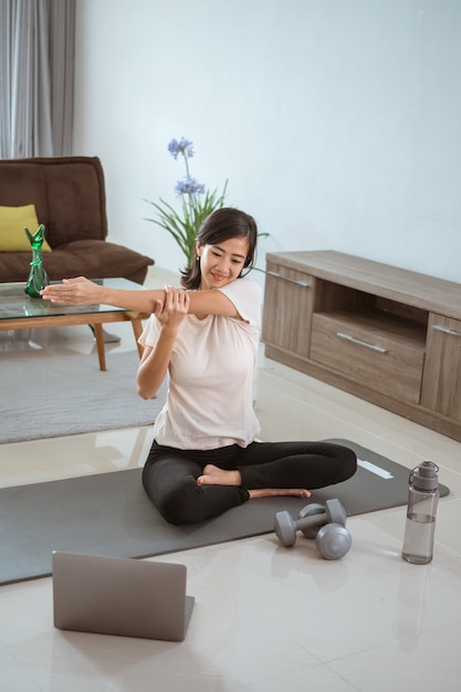 Young girl looking at laptop and doing exercises at home by her self